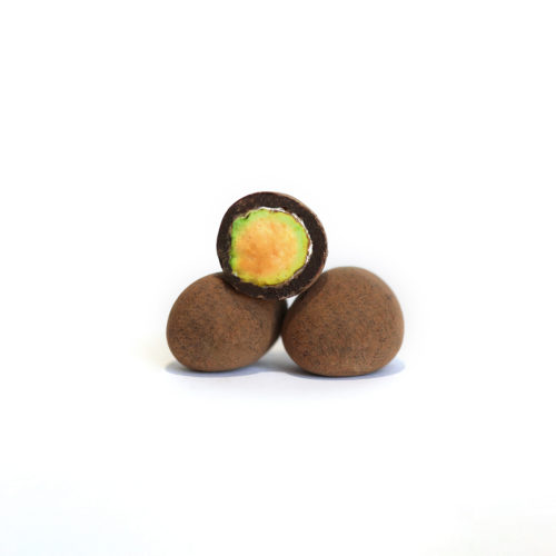 Trois pistaches enrobées au chocolat, une pistache coupée avec l'intérieur visible.